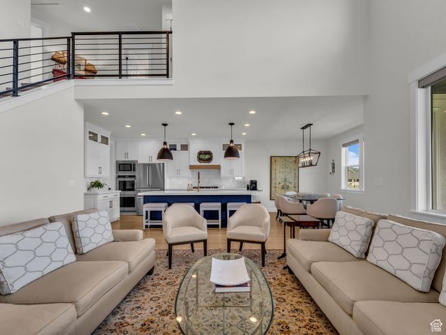 Living room featuring light wood finished floors, a towering ceiling, and recessed lighting | Image 10