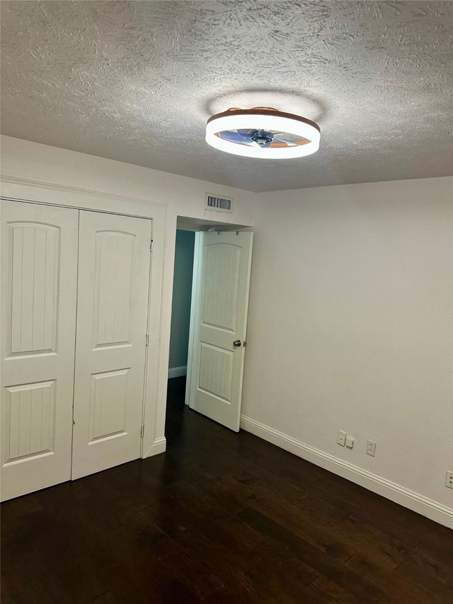 secondary bedroom featuring dark wood-style floors, a textured ceiling, and a closet | Image 28