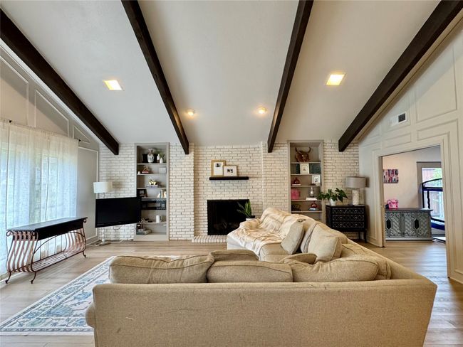 Living area with a brick wall and fireplace and wide plank luxury vinyl floor. | Image 5
