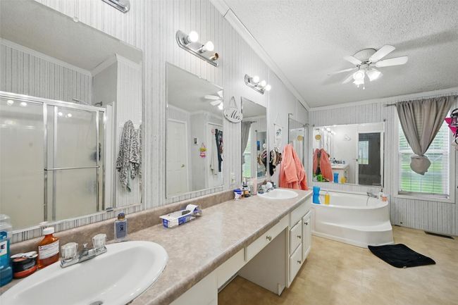 Bathroom featuring ornamental molding, a ceiling fan, double vanity, a garden tub, and a shower stall | Image 11