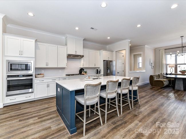 Kitchen offers quartz counters, stainless steel appliances, gas cook top, huge 8' island, custom lighting, plenty of cabinets for storage & pantry! | Image 7