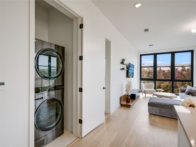 Laundry room featuring visible vents, baseboards, light wood-type flooring, stacked washer and dryer, and laundry area | Image 11