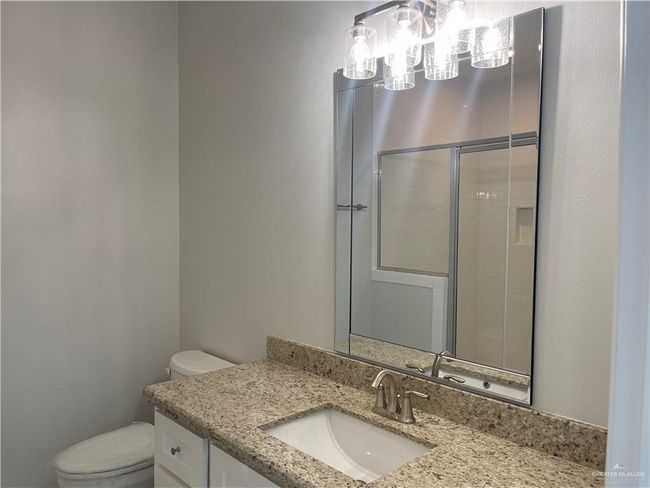Bathroom featuring toilet, vanity, a chandelier, and tiled shower | Image 11