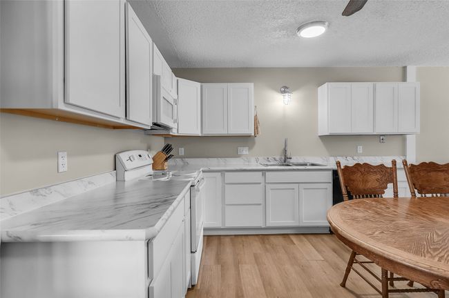 Kitchen featuring white appliances, a sink, light wood-style floors, light countertops, and white cabinetry | Image 13