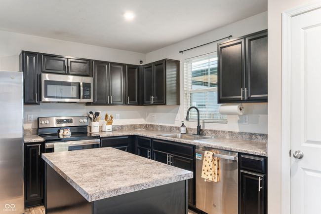 Kitchen with the warmer darker cabinets & center Island | Image 9