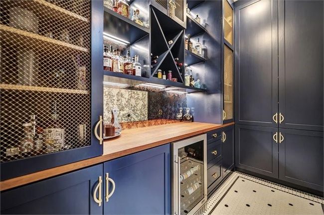 Stylish bar features custom cabinetry, a built-in wine fridge, shelving with accent lighting, and a beautiful wood countertop—perfect for entertaining and storage. | Image 10