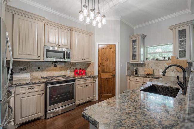 You will love this spacious kitchen and all the appliances. It comes with stove/oven combination, microwave, large refrigerator, dishwasher, built in wine cooler, granite counter tops. The sink is hammered copper and matches the counter tops perfectly. The doors are solid wood and there is a large pantry. There are plenty of storage places for all of your things, and pendant lighting adds to the flow of light from the many windows. | Image 20