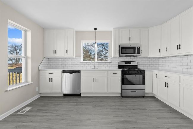 Kitchen with appliances with stainless steel finishes, a sink, white cabinets, and tasteful backsplash | Image 5