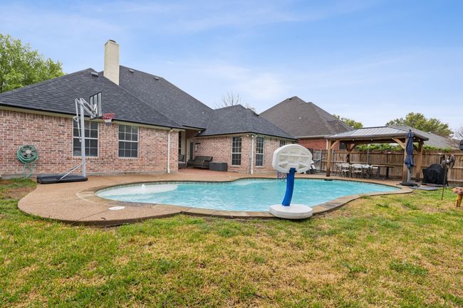 View of swimming pool featuring fence, a fenced in pool, a gazebo, a yard, and a patio area | Image 5