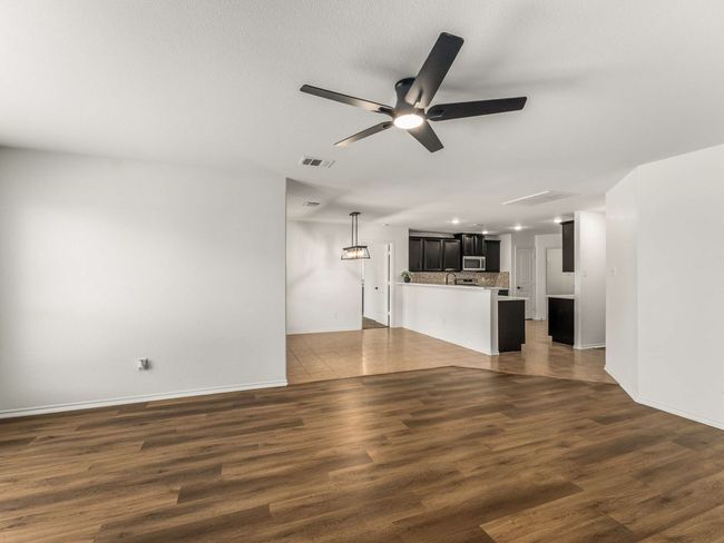 Unfurnished living room with ceiling fan, dark wood-style flooring, and recessed lighting | Image 12