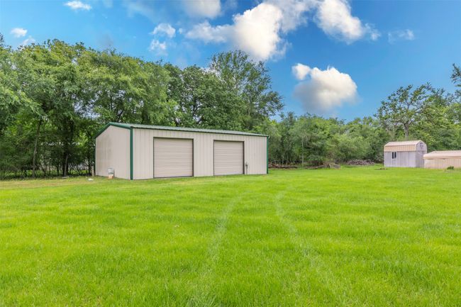 View of yard featuring a garage and an outbuilding | Image 25