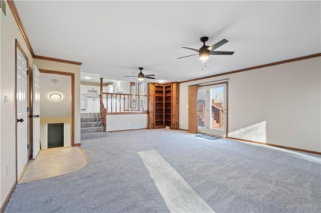Unfurnished living room featuring stairs, ornamental molding, ceiling fan, light carpet, and baseboards | Image 36