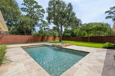 Step out from the living area to a beautifully landscaped backyard featuring a heated saltwater pool and hot tub, perfect for year-round enjoyment. The sound system also extends to this patio area. | Image 3