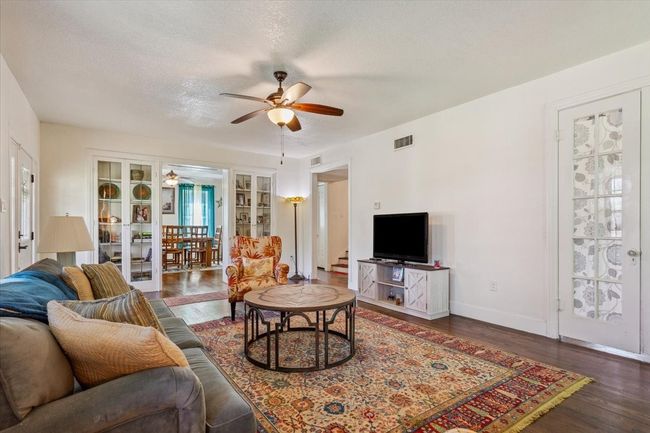 Living room with ceiling fan, a textured ceiling, visible vents, wood finished floors, and baseboards | Image 7