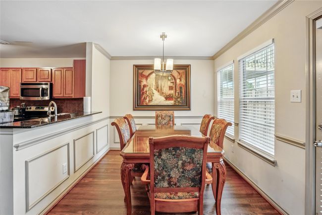 Dining space featuring ornamental molding, dark wood-style flooring, and a chandelier | Image 12