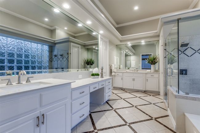 The primary bathroom offers separate sink areas, a glass shower, jetted tub, and a large walk-in closet. | Image 18