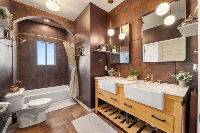 Full bathroom featuring double vanity, shower / bath combination with curtain, toilet, and a sink | Image 25