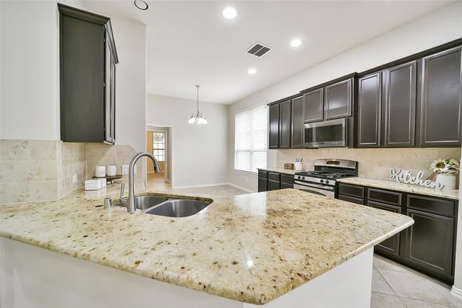 A closer look into the kitchen and you will find neutral, granite countertops and sleek espresso cabinetry. | Image 7