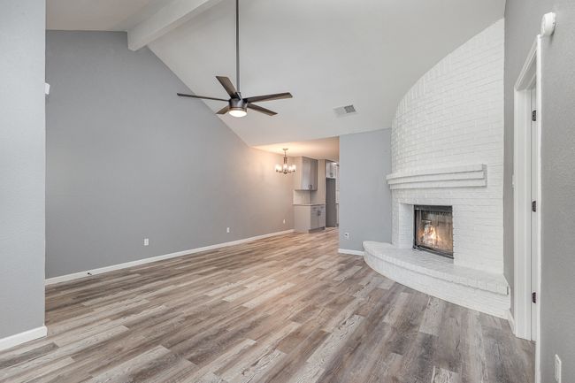 Unfurnished living room with a fireplace, light wood-style flooring, ceiling fan, a chandelier, and baseboards | Image 12