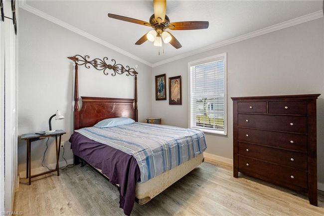 Bedroom with ornamental molding, light wood finished floors, a ceiling fan, and baseboards | Image 22