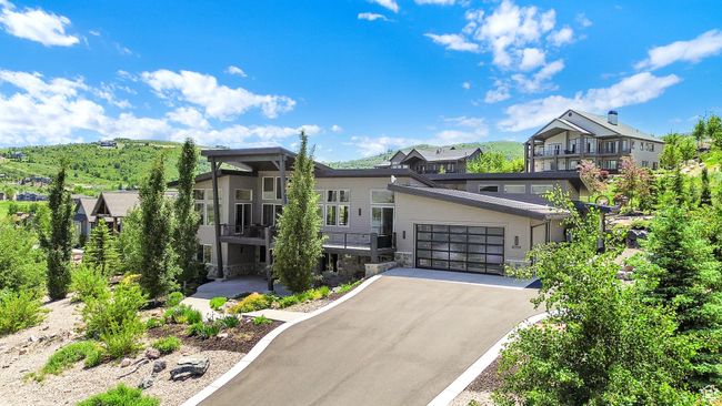 Modern home with stone siding, asphalt driveway, a garage, and a residential view | Image 102