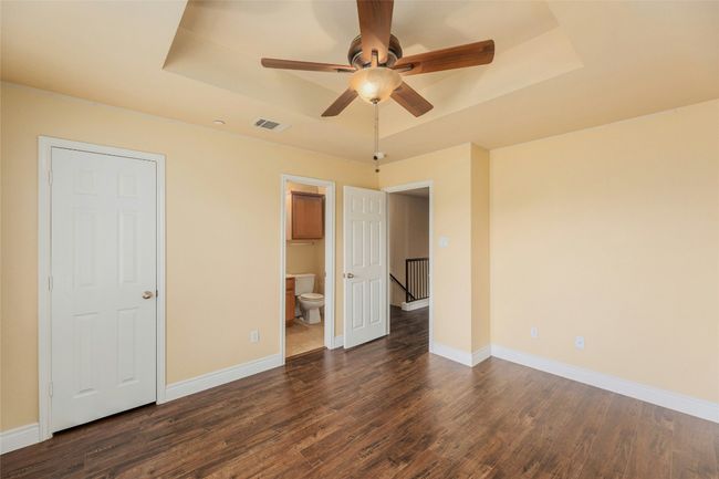 Unfurnished bedroom featuring a raised ceiling, dark wood finished floors, ensuite bathroom, and a ceiling​​‌​​​​‌​​‌‌​‌‌​​​‌‌​​‌‌​‌​​​​​‌ fan | Image 21