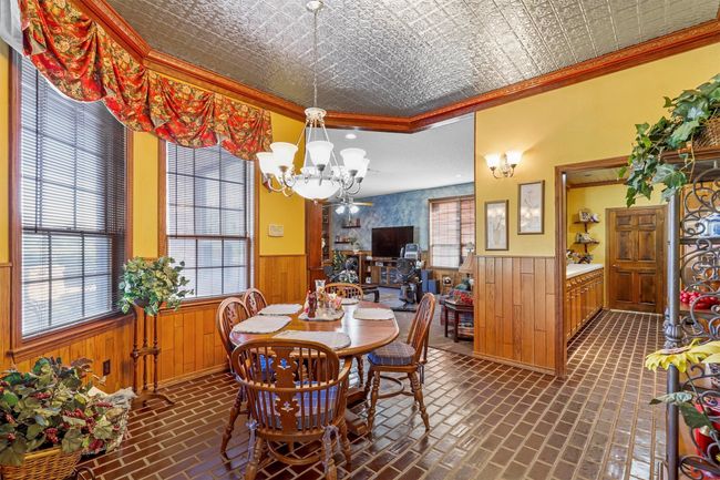 Dining space featuring ornamental molding, wooden walls, and a notable chandelier | Image 14