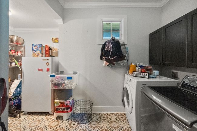 Laundry room with cabinet space, separate washer and dryer, crown molding, and baseboards | Image 19