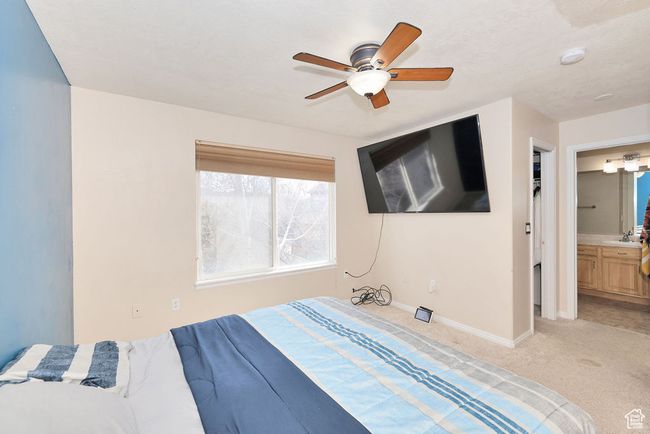 Bedroom with connected bathroom, a ceiling fan, light carpet, a sink, and baseboards | Image 22