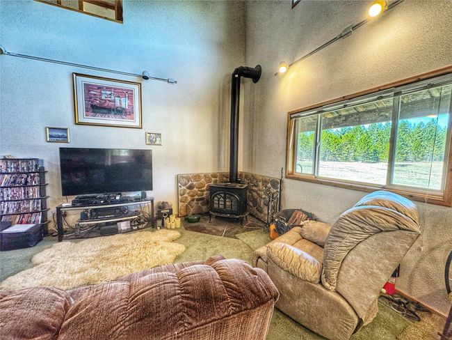 Living room featuring a textured wall, a wood stove, and carpet | Image 21