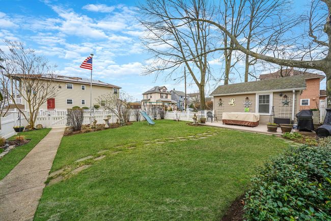 View of yard featuring a hot tub, a fenced backyard, a playground, and a patio area | Image 25