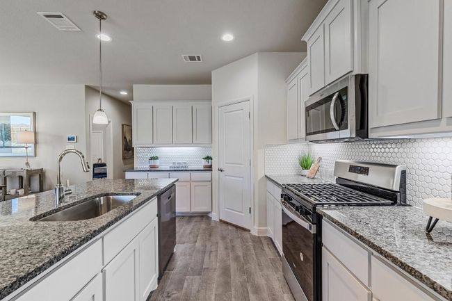 Kitchen featuring appliances with stainless steel finishes, white cabinets, recessed lighting, backsplash, and stone countertops | Image 5
