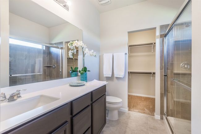 Bathroom with tile patterned flooring, a shower stall, a walk in closet, toilet, and vanity | Image 27