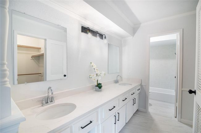 The primary bathroom has a double-sink vanity with a sleek white countertop and ample storage space. Mirrors are to be installed. The primary bathroom has a shower/tub combo. | Image 24