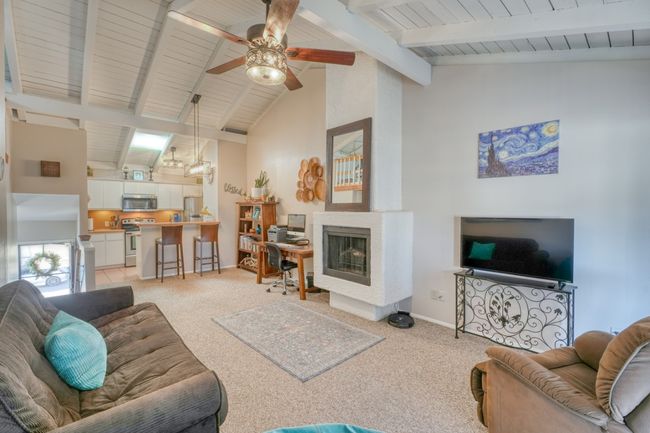 Living area featuring light colored carpet, a multi sided fireplace, and ceiling fan upper unit | Image 20