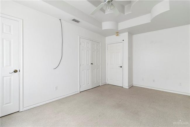 Unfurnished bedroom featuring carpet flooring, a raised ceiling, and ceiling fan | Image 12