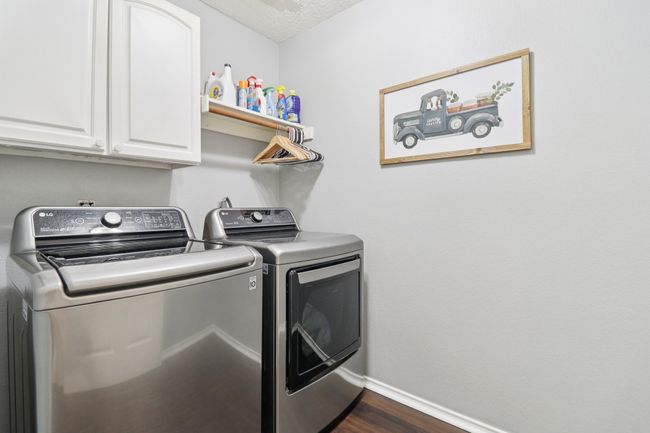 Laundry area featuring cabinet space, washing machine and clothes dryer, baseboards, and dark wood finished floors | Image 32