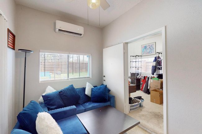 Carpeted living area with a ceiling fan and a wall mounted air conditioner | Image 26