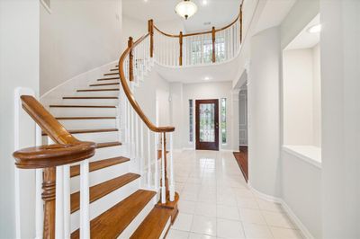 Grand entrance featuring a dramatic curved staircase and soaring ceilings. | Image 2