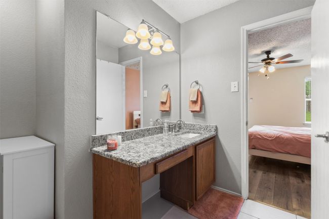 Ensuite bathroom featuring vanity, a ceiling fan, baseboards, wood finished floors, and a textured wall | Image 21
