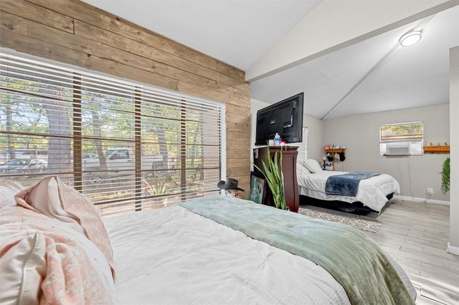 Bedroom featuring wooden walls, baseboards, wood finished floors, and lofted ceiling | Image 28