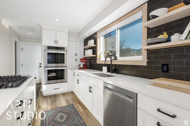 Kitchen with open shelves, backsplash, stainless steel appliances, and a sink | Image 12