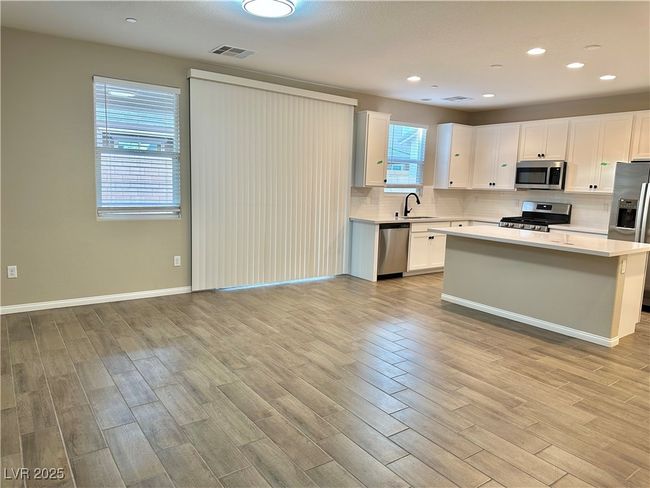 Kitchen featuring light wood finished floors, appliances with stainless steel finishes, light countertops, and backsplash | Image 19