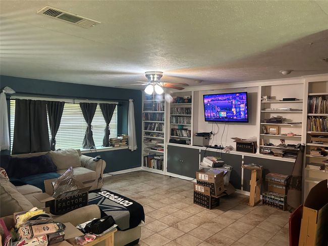 Tiled living area with a ceiling fan, a textured ceiling, built in features, and baseboards | Image 17