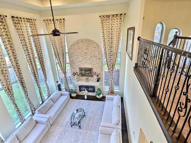 Living area featuring a high ceiling and a glass covered fireplace | Image 4