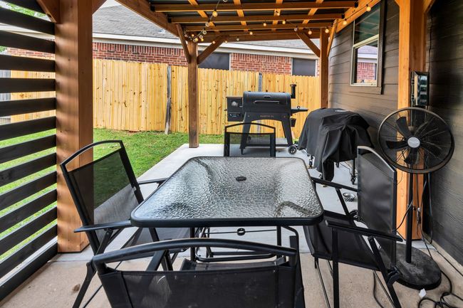 View of patio with outdoor dining area, fence, and a grill | Image 29