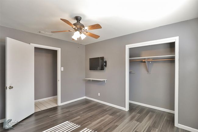 Unfurnished bedroom with ceiling fan, dark hardwood / wood-style floors, and a closet | Image 16