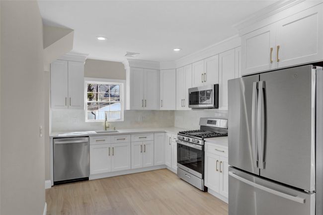 Kitchen with visible vents, white cabinets, appliances with stainless steel finishes, light countertops, and a sink | Image 5