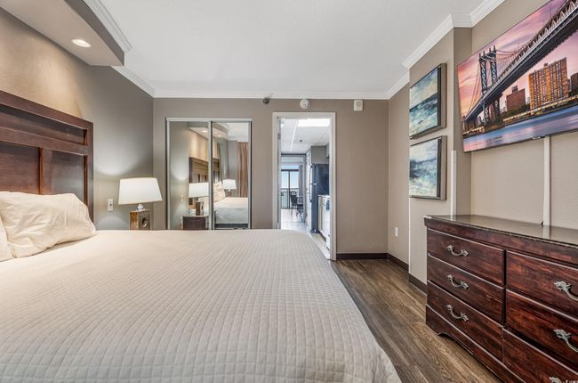 Bedroom with ornamental molding, dark wood finished floors, and a closet | Image 4