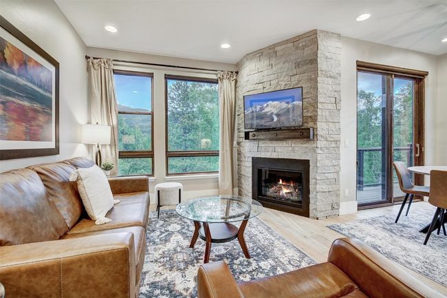 Living area with wood finished floors, recessed lighting, a stone fireplace, and baseboards | Image 15